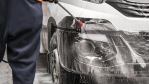 Person using a pressure washer to clean the front of a commercial vehicle, showcasing fleet detailing services relevant to vehicle maintenance in West Boylston.