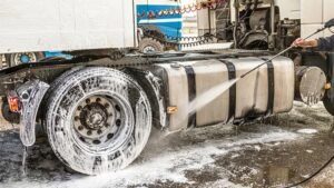 Fleet detailing service in West Boylston, showcasing a truck being pressure washed, with focus on tire and chassis cleaning for optimal vehicle maintenance.