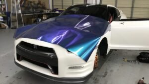 Car undergoing vinyl wrap installation with a vibrant blue and purple design, showcasing Aesthetic Auto Solutions' vehicle customization services in West Boylston.