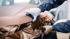 Person applying a vinyl wrap to a vehicle, showcasing expertise in vehicle customization and protection, relevant to Aesthetic Auto Solutions' services in West Boylston.