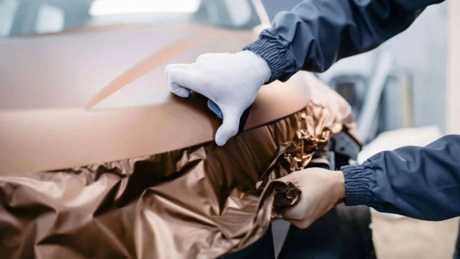 Person applying a vinyl wrap to a vehicle, showcasing vehicle transformation and protection, relevant to vinyl wrapping services.